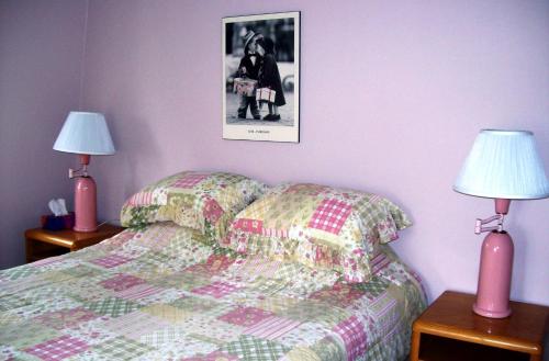 um quarto com uma cama com dois candeeiros e uma imagem na parede em La Belle Époque em La Malbaie