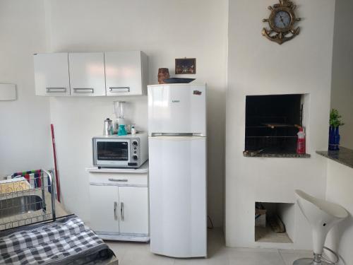 cocina blanca con nevera y microondas en Apartamento BLUE 04 - 100 metros da praia en São Lourenço do Sul