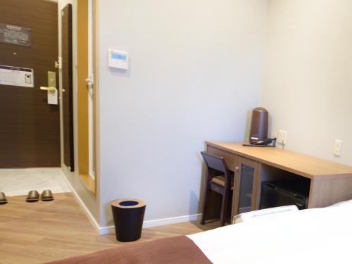 a room with a bed and a desk with a television at Hotel Abest Grande Okayama in Okayama