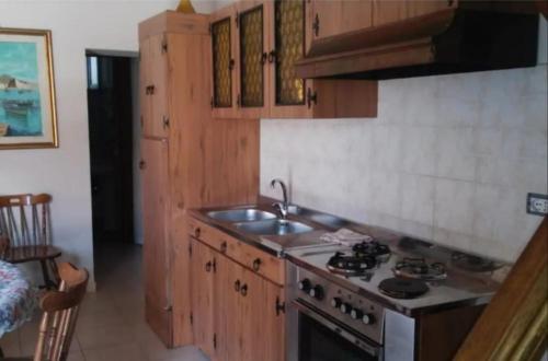cocina con armarios de madera, fogones y fregadero en Casa indipendente a pochi passi dal mare, en Bova Marina
