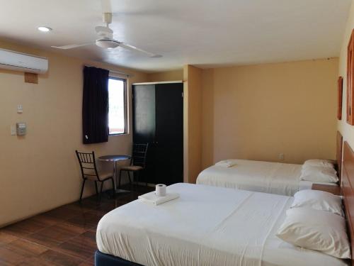 a hotel room with two beds and a table and chairs at Hotel Bugambilia Campeche in Campeche