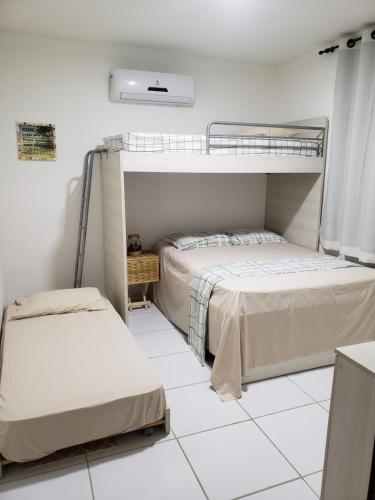 two beds in a room with white tile floors at Chaleville Coqueiro 1001 in Luis Correia