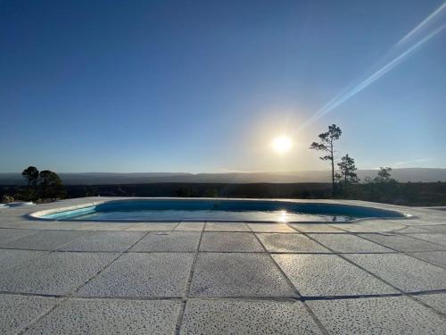 una piscina circular en un patio con el sol al fondo en Cabañas PAIGÜEN, en Villa Yacanto