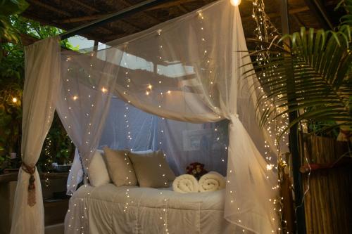 a canopy bed with white curtains and lights at Hacienda Boutique B&B and Spa Solo Adultos in Cozumel