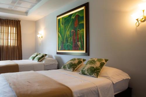 Cette chambre comprend deux lits et un tableau mural. dans l'établissement Hotel Kevin, à Los Santos