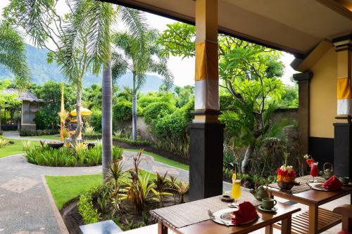 
a patio area with tables, chairs, and umbrellas at Taruna Boutique Homestay & Spa in Pemuteran
