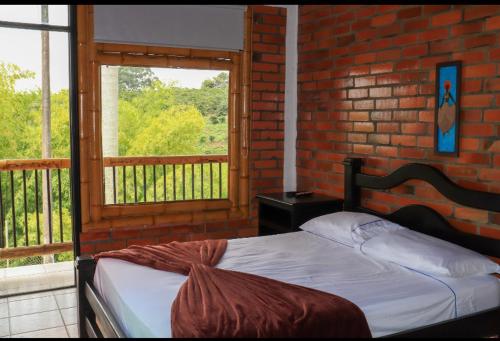 1 dormitorio con cama y pared de ladrillo en Palmas De Santa Elena, en Quimbaya