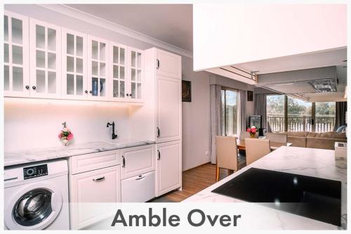 a kitchen with white cabinets and a living room at Amble at Hahndorf in Hahndorf