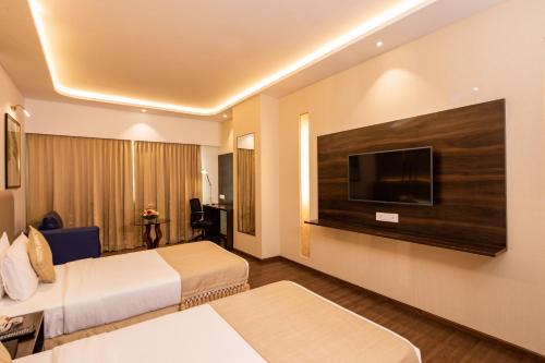 a hotel room with two beds and a flat screen tv at Goldfinch Hotel Bangalore in Bengaluru