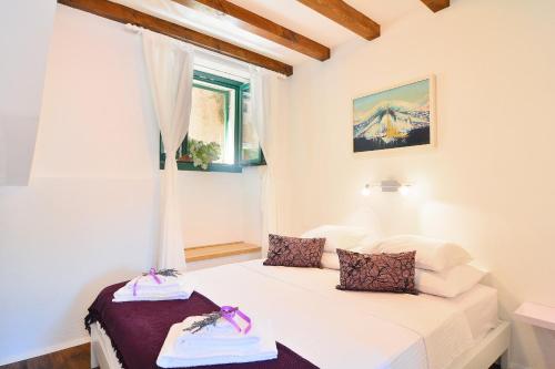 a bedroom with a white bed and white walls at Apartments and Rooms Kampanel in Hvar