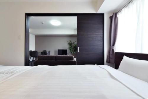 1 dormitorio con cama blanca y espejo grande en Suncourt Hongo Dori Garden Hills / Vacation STAY 7609, en Sapporo