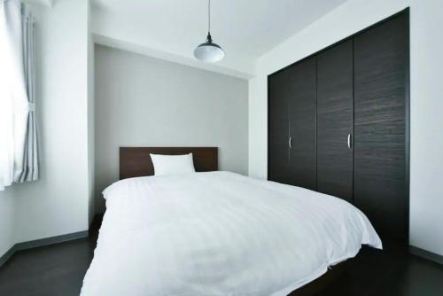 a bedroom with a white bed and a black cabinet at Suncourt Hondori Garden Hills / Vacation STAY 7587 in Sapporo
