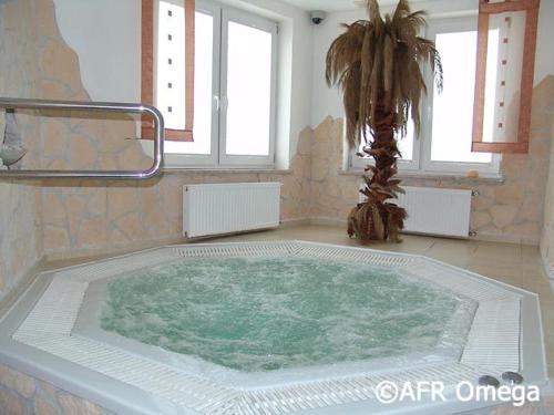 a large bath tub in a room with a palm tree at Brydar with Sauna, Swimming Pool and Jacuzzi in Mielno