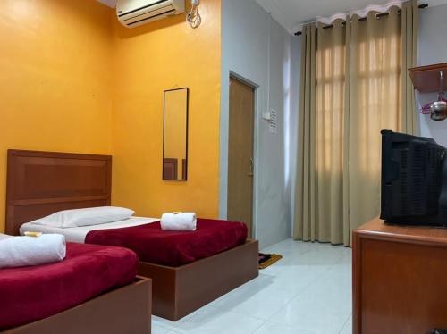 a hotel room with two beds and a television at Samudera Hotel in Kampung Kuala Besut