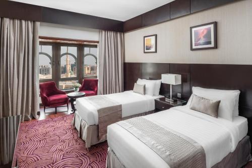 a hotel room with two beds and a red chair at Taiba Front Hotel in Medina