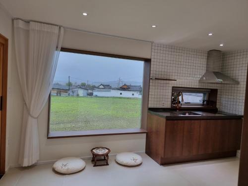 a kitchen with a large window with a view of a field at Stay Gyeongju in Gyeongju