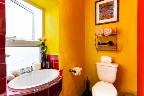 a yellow bathroom with a sink and a toilet at Garlands Del Rio Riverside Boutique Hotel in Puerto Vallarta
