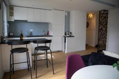 een keuken en een woonkamer met 2 barkrukken bij LES 2 LIONS moderne confort proche transports in Tours