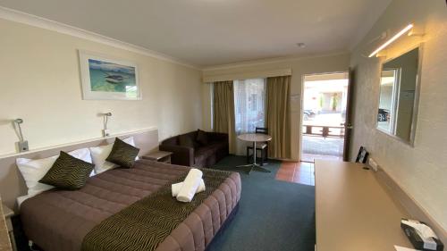 Habitación de hotel con cama y sala de estar. en Sapphire City Motor Inn en Inverell