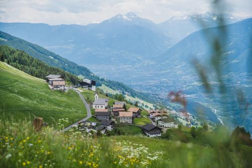 a village on a hill with mountains in the background at Ferienwohnungen Wiesbauer in Schenna