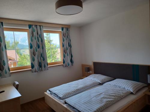 a bed in a bedroom with two windows at Chalet Petra in Aich