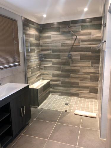 a bathroom with a shower and a sink at Whispering Pines Country Estate in Magaliesburg