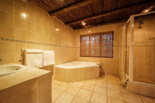 a large bathroom with a tub and a sink at Whispering Pines Country Estate in Magaliesburg