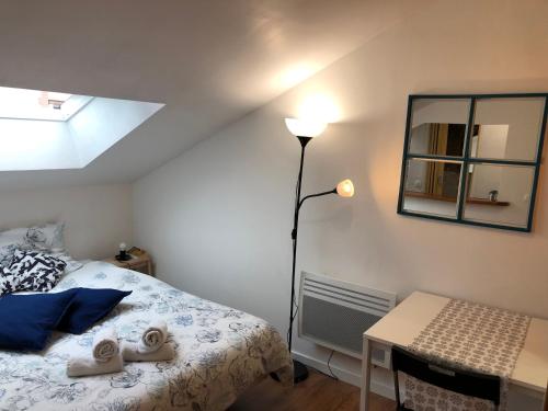 a bedroom with a bed and a lamp and a desk at Studio La Belle Vie in Suresnes