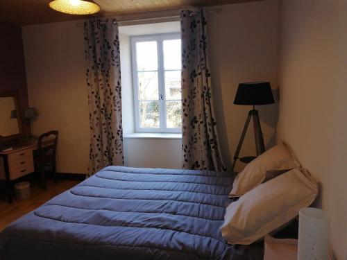 een slaapkamer met een bed met een blauw dekbed en een raam bij Chambres et table d'hôtes Régord'âne in Le Brignon