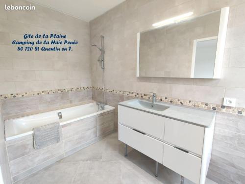 La salle de bains est pourvue d'un lavabo, d'une baignoire et d'un miroir. dans l'établissement Camping la Haie Penée ****, à Saint-Quentin-en-Tourmont