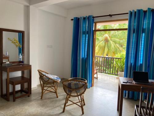 a living room with blue curtains and a table and chairs at Garden Villa Talalla in Talalla