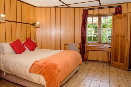 a bedroom with a bed with red pillows and a window at Kings Lodge Hotel in Hogsback