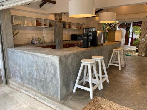 a kitchen with two stools and a counter with a microwave at Una Beach Hotel & OLU Cafe in Unawatuna