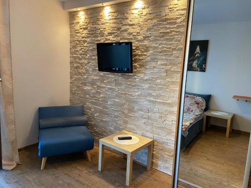 a room with a chair and a tv on a brick wall at Apartament Promenada II in Ostróda