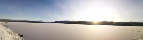 a frozen lake with the sun in the background at Tärnaby Rooms & Apartments in Tärnaby
