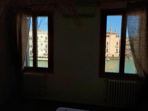 a room with three windows with a view of the water at Residenza La Veranda a Rialto in Venice