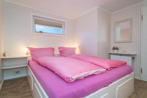 提努姆Schallers Hüs 5 - Bungalow的卧室内的一张带粉红色床单的大床