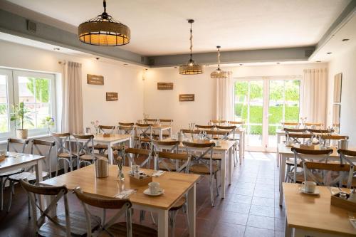 a dining room with tables and chairs and windows at Hotel am Uckersee in Röpersdorf