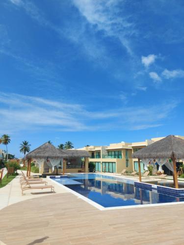 ein Pool mit Sonnenschirmen und ein Resort in der Unterkunft Curta Milagres 31,condominio Morada do Toque in São Miguel dos Milagres