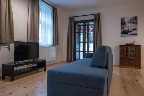 a living room with a blue couch and a tv at Tschardakenhof Appartements in Lutzmannsburg