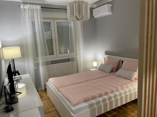 a bedroom with a large bed and a window at Apartmani Sombor in Sombor