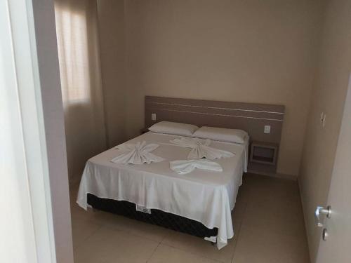 アラカティにあるVILAS NA PRAIA RESIDENCE O PARAÍSO É AQUIのベッドルーム1室(白いシーツと枕のベッド1台付)