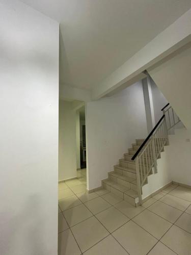 a hallway with a staircase in a white building at SarahAisya homestay in Melaka