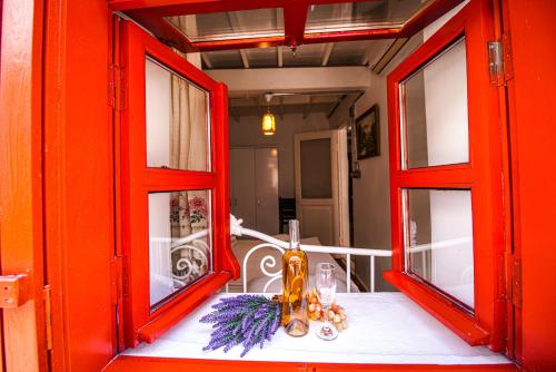 una mesa con 2 ventanas rojas en una habitación en Grape Island Bozcaada Guest House, en Canakkale