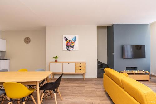 uma sala de estar com um sofá amarelo e uma mesa em LE DUPLEX - T6 COEUR DE ViLLE em Agen