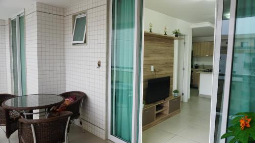 a balcony with a table and a television in a house at Dubai residência in Cabo Frio