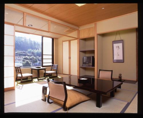 Habitación con mesa, sillas y ventana grande. en Marukyu Ryokan, en Izu