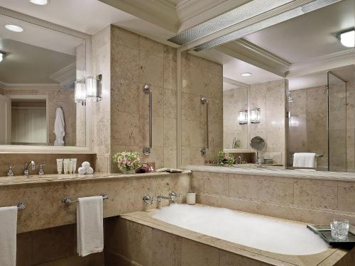 a bathroom with a large tub and a large mirror at The Langham Melbourne in Melbourne