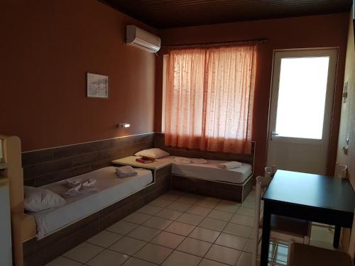 a room with two beds and a window at Asteraki ApartHotel in Gouvia