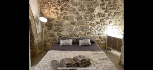 une chambre avec un lit et un mur en pierre dans l'établissement LEMON SUITE Ortigia, à Syracuse